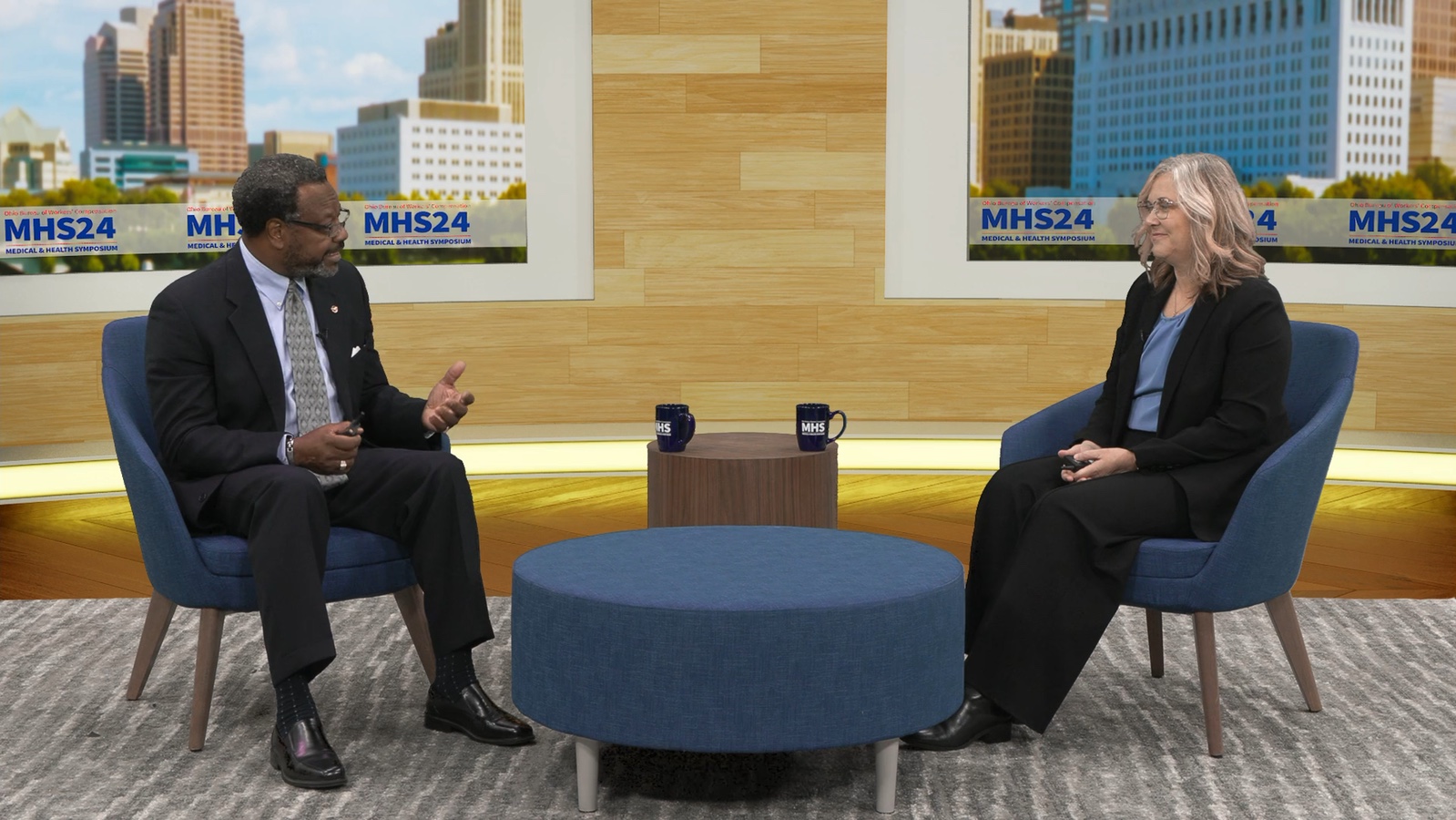Two presenters in the BWC virtual studio, with the full broadcast set visible