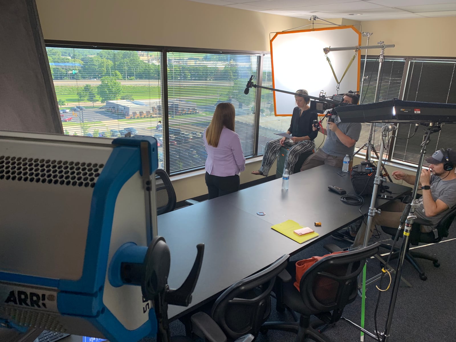 Camera, lighting and crew filming an interview in an office overlooking the city